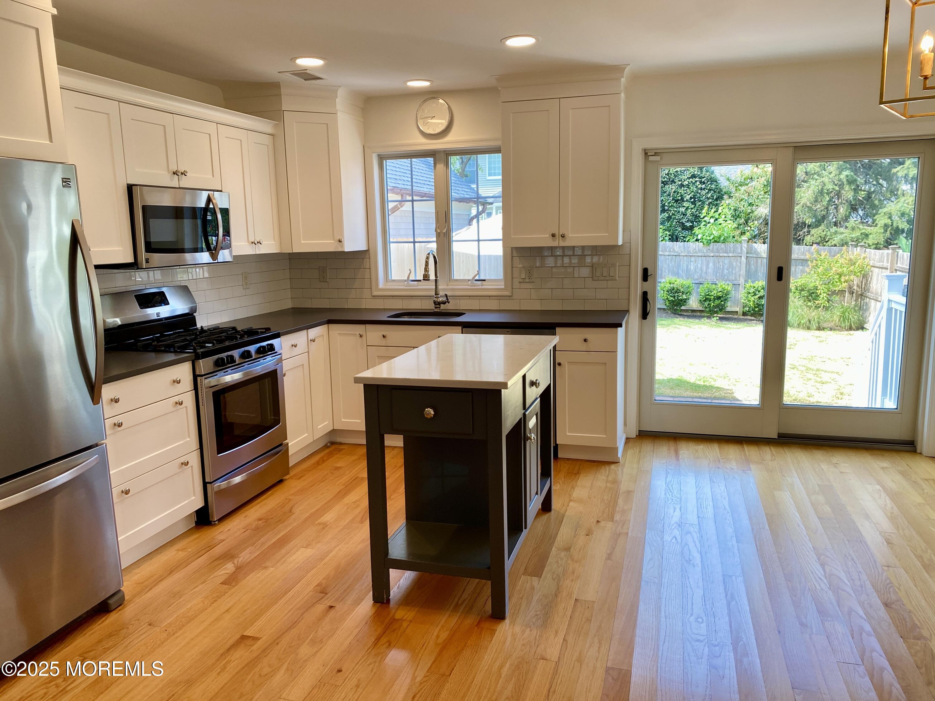 32 1st Street Rumson, NJ 07760 - Photo 8 of 25 a kitchen with stainless steel appliances granite countertop wooden floor a stove a sink dishwasher and a microwave oven with wooden floor