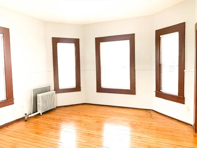 a view of an empty room with window and wooden floor