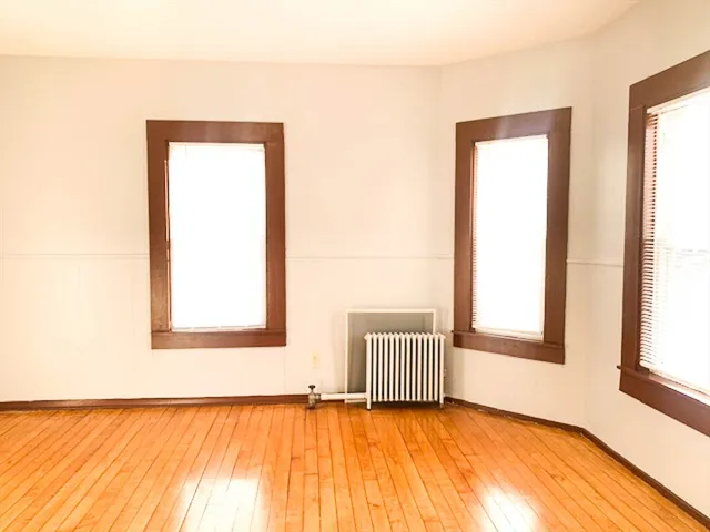 a view of an empty room with a window and wooden floor