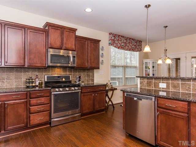 2903 Red Grape Drive Raleigh, NC 27607 - Photo 5 of 25 a kitchen with stainless steel appliances granite countertop a stove a sink and a wooden floors