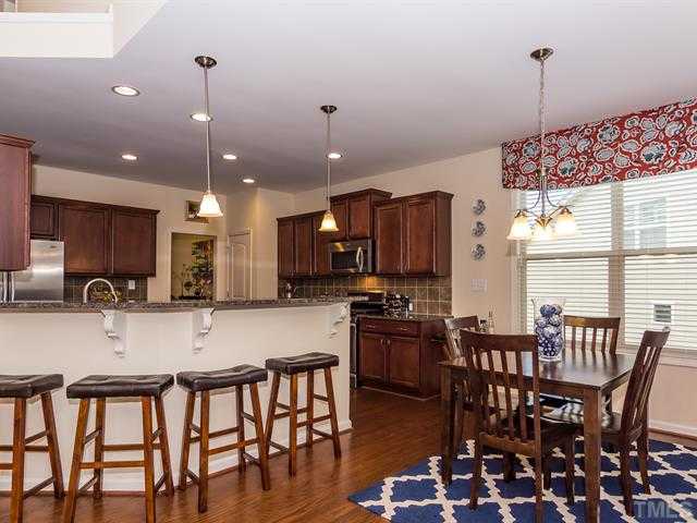2903 Red Grape Drive Raleigh, NC 27607 - Photo 8 of 25 a kitchen with stainless steel appliances granite countertop a stove a refrigerator a kitchen island a dining table and chairs