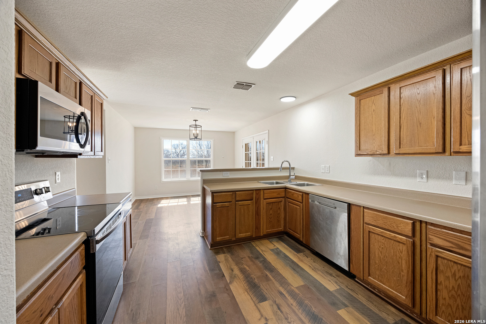 18181 Senior Road Von Ormy, TX 78073 - Photo 16 of 46 a kitchen with cabinets wooden floor and a sink