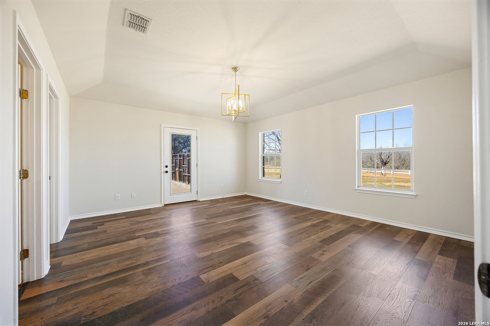 18181 Senior Road Von Ormy, TX 78073 - Photo 21 of 46 an empty room with wooden floor chandelier and windows