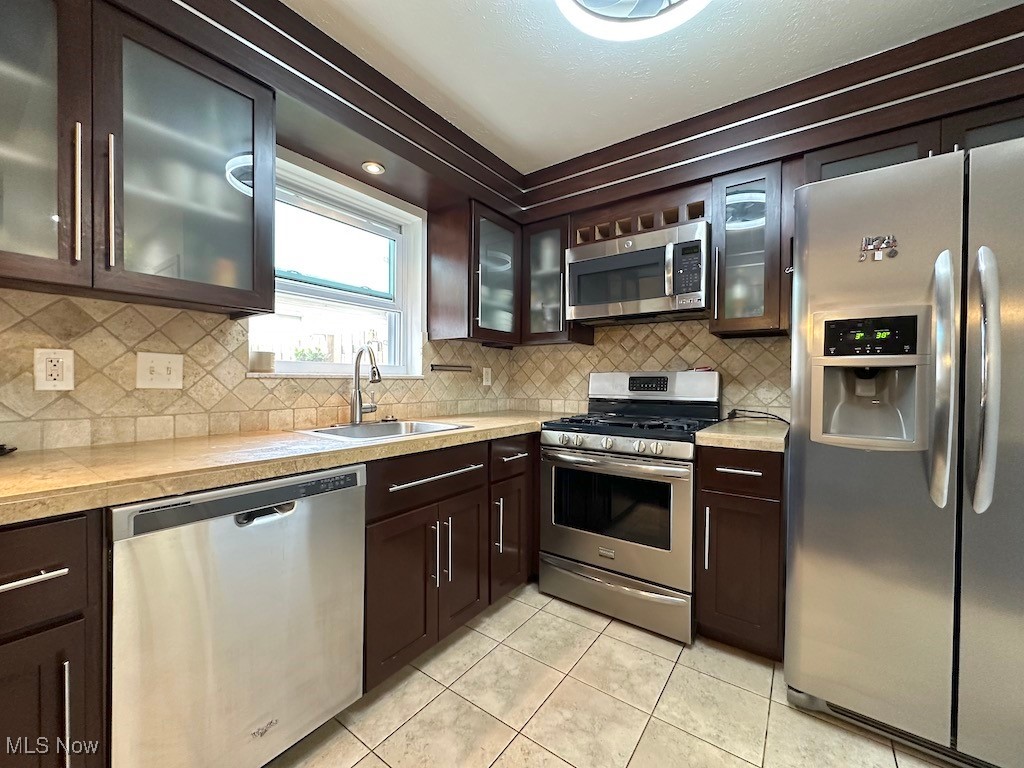6482 State Road, Unit E1 Parma, OH 44134 - Photo 12 of 48 Kitchen with stainless steel appliances, a sink, dark brown cabinets, light countertops, and light tile patterned floors