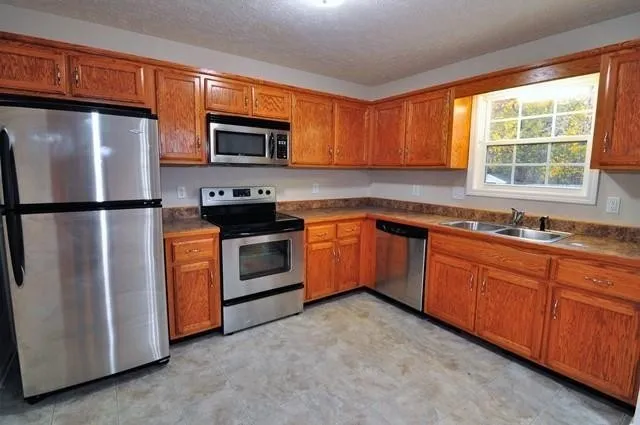 a kitchen with stainless steel appliances granite countertop a stove a sink dishwasher a refrigerator and a microwave