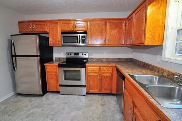 a kitchen with stainless steel appliances granite countertop a stove a sink and a microwave