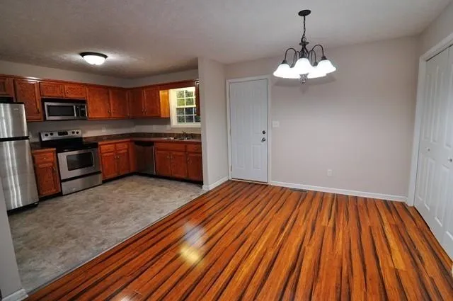 a kitchen with stainless steel appliances granite countertop a sink dishwasher and a stove with wooden floor