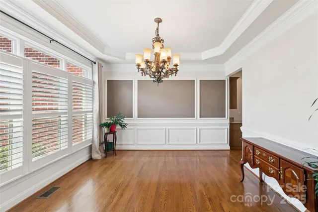 a view of a hallway with wooden floor and chandelier