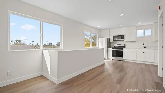 a view of a kitchen with wooden floor and electronic appliances