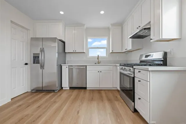 a kitchen with stainless steel appliances a sink cabinets and a wooden floor
