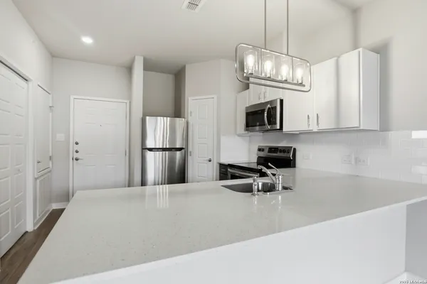 a kitchen with stainless steel appliances granite countertop a refrigerator a microwave oven a sink a stove and a refrigerator