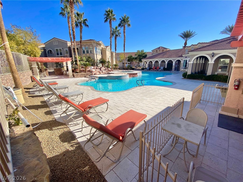 10550 West Alexander Road, Unit 1131 Las Vegas, NV 89129 - Photo 17 of 18 An inviting pool area with ample lounging space, complemented by surrounding residential architecture under a clear sky.