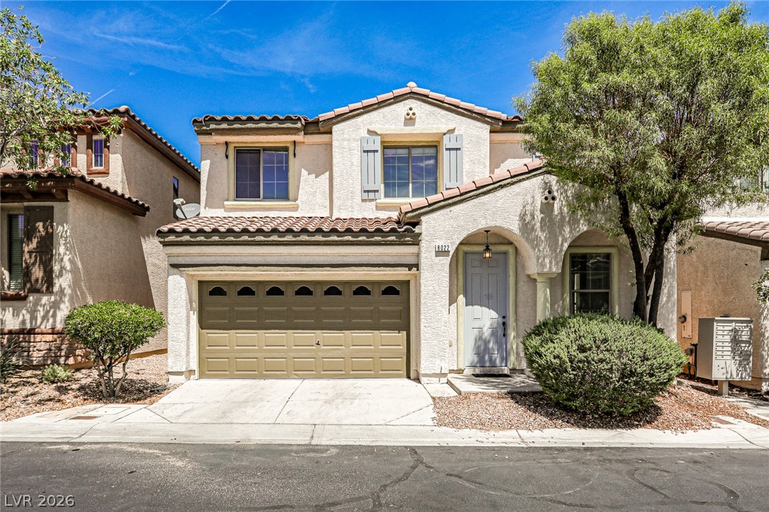 Spanish-style stucco facade features classic tile roofing, arched entryway details, and attached garage storage.
