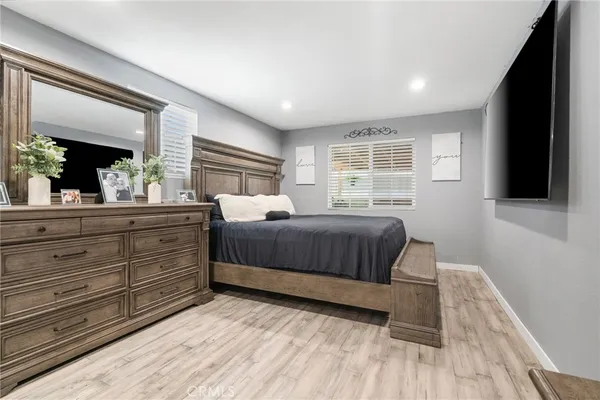 a bedroom with a large bed and a flat tv screen on dresser