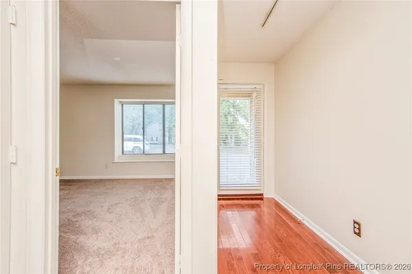 a view of an empty room with wooden floor and a window