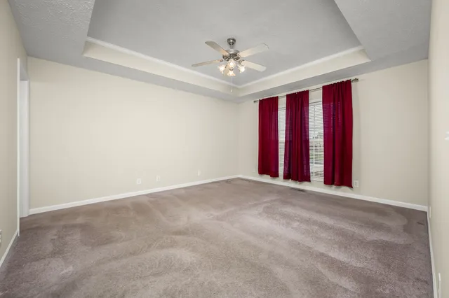 an empty room with chandelier fan and windows