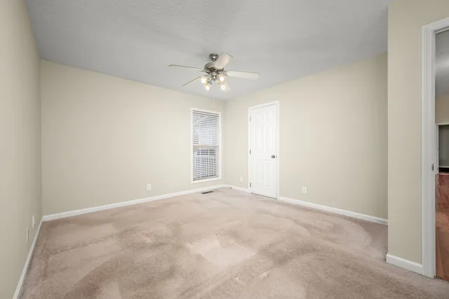 an empty room with a ceiling fan and a window