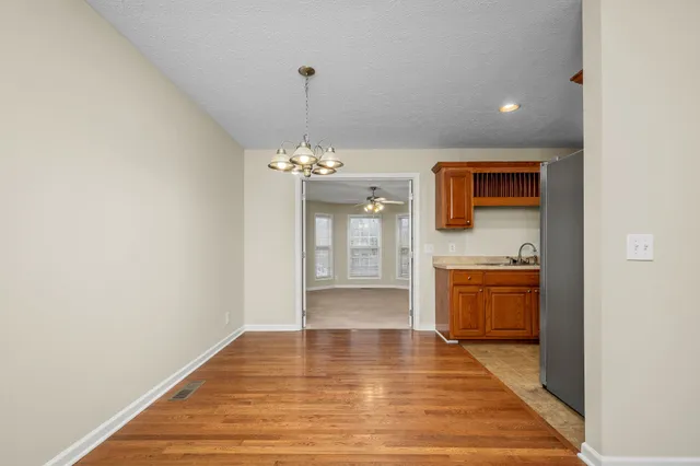 a view of an empty room with a kitchen and a window