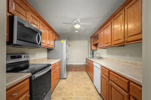 a kitchen with stainless steel appliances granite countertop a refrigerator a stove top oven a sink dishwasher and wooden cabinets