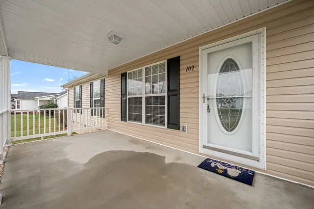 a view of a white house with a yard and large tree