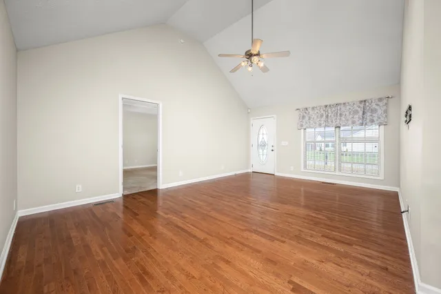 a view of an empty room with wooden floor and a window