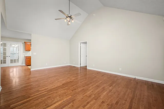 a view of an empty room with wooden floor and a window