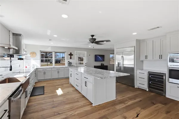 a kitchen with stainless steel appliances kitchen island wooden floors and white cabinets
