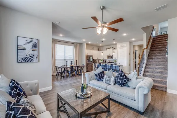 a living room with furniture kitchen view and a chandelier