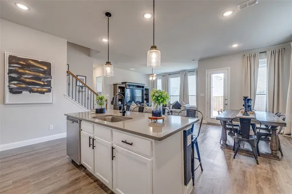 a dining hall with stainless steel appliances kitchen island granite countertop a stove a sink a dining table and chairs with wooden floor