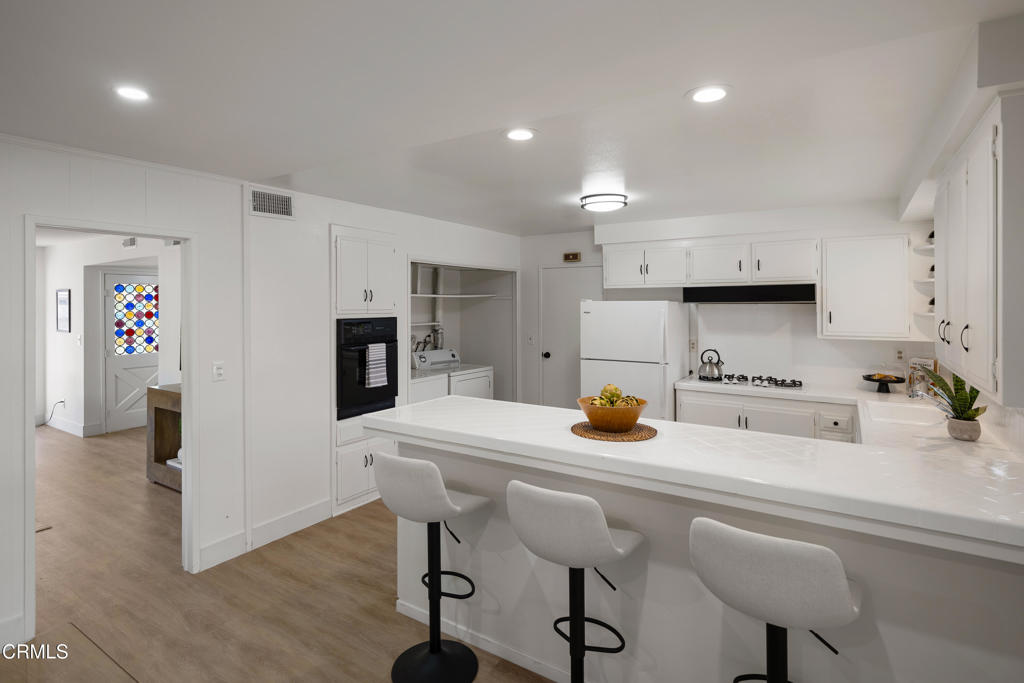 3514 St Elizabeth Road Glendale, CA 91206 - Photo 18 of 75 a kitchen with a sink a stove a refrigerator and white cabinets with wooden floor