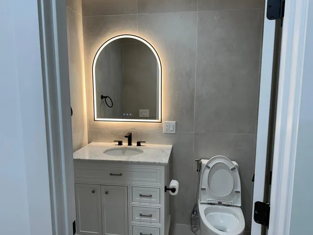 a bathroom with a granite countertop toilet a sink and a mirror