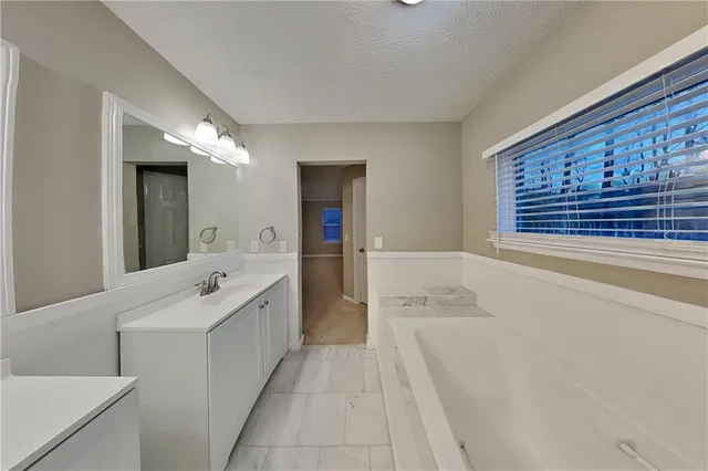 a spacious bathroom with a tub sink and mirror