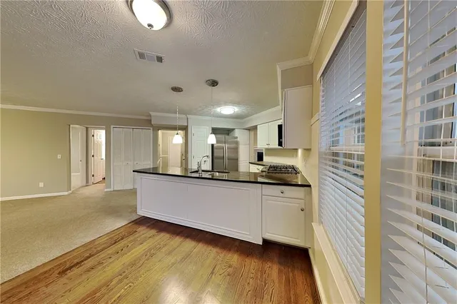 a large white kitchen with granite countertop a sink and dishwasher a stove with wooden floor