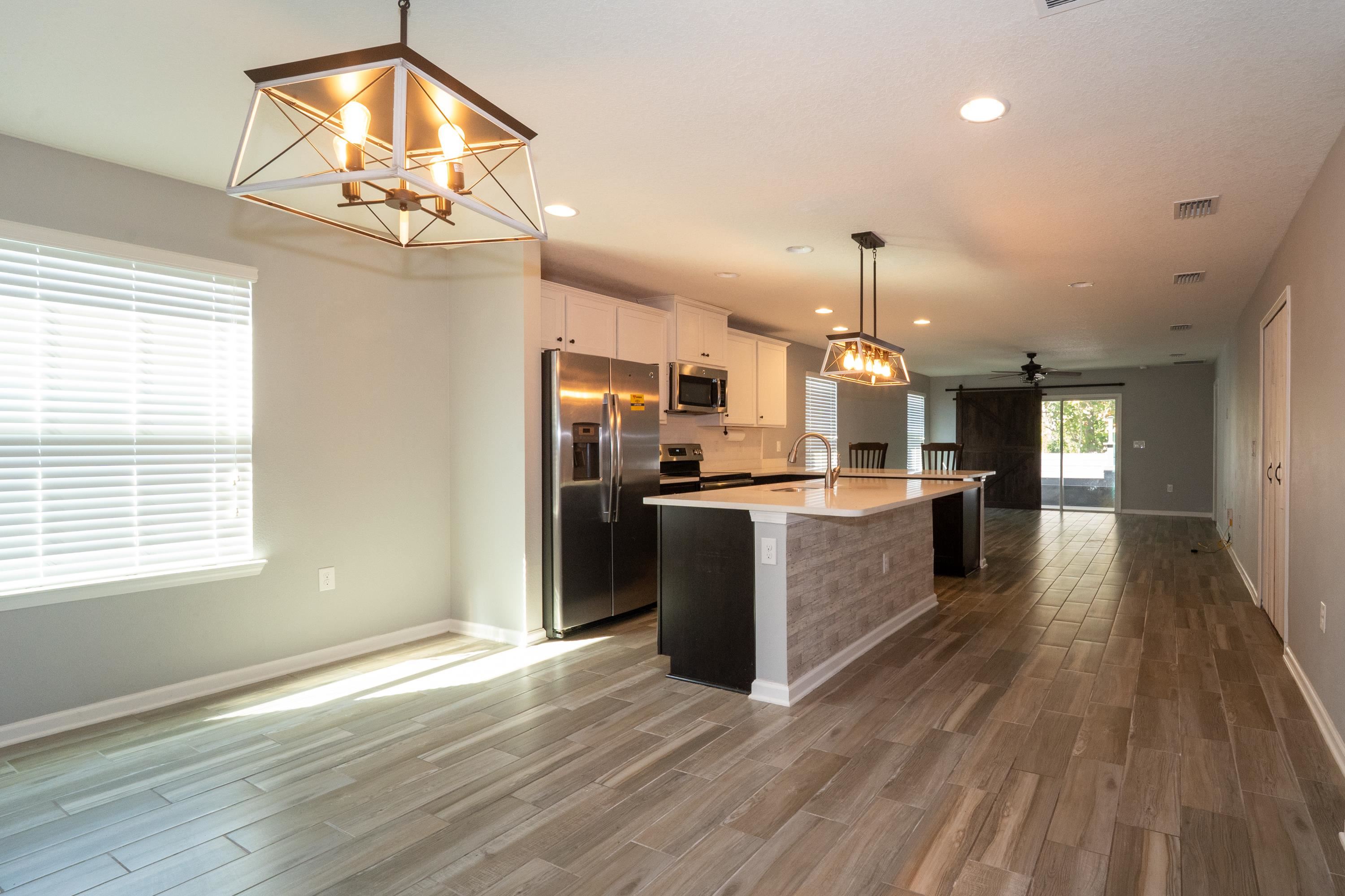 415 Santorini Court St. Augustine, FL 32086 - Photo 52 of 52 a kitchen with kitchen island granite countertop a refrigerator a sink dishwasher a stove and a dining table with wooden floor
