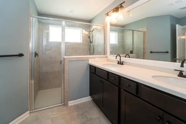 a bathroom with a double vanity sink mirror and shower