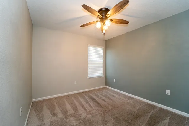 an empty room with a window and a fan
