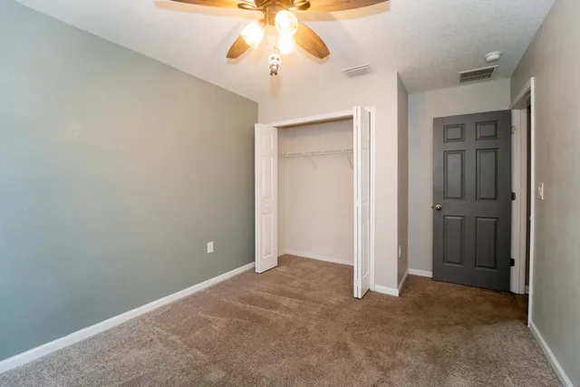 an empty room with a chandelier fan and a bathroom