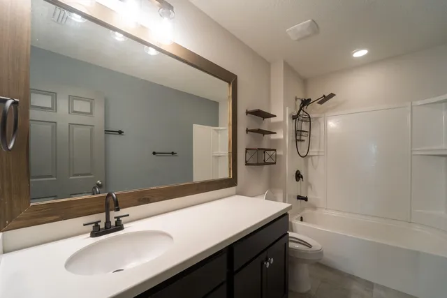 a bathroom with a sink double vanity granite tub shower and a mirror