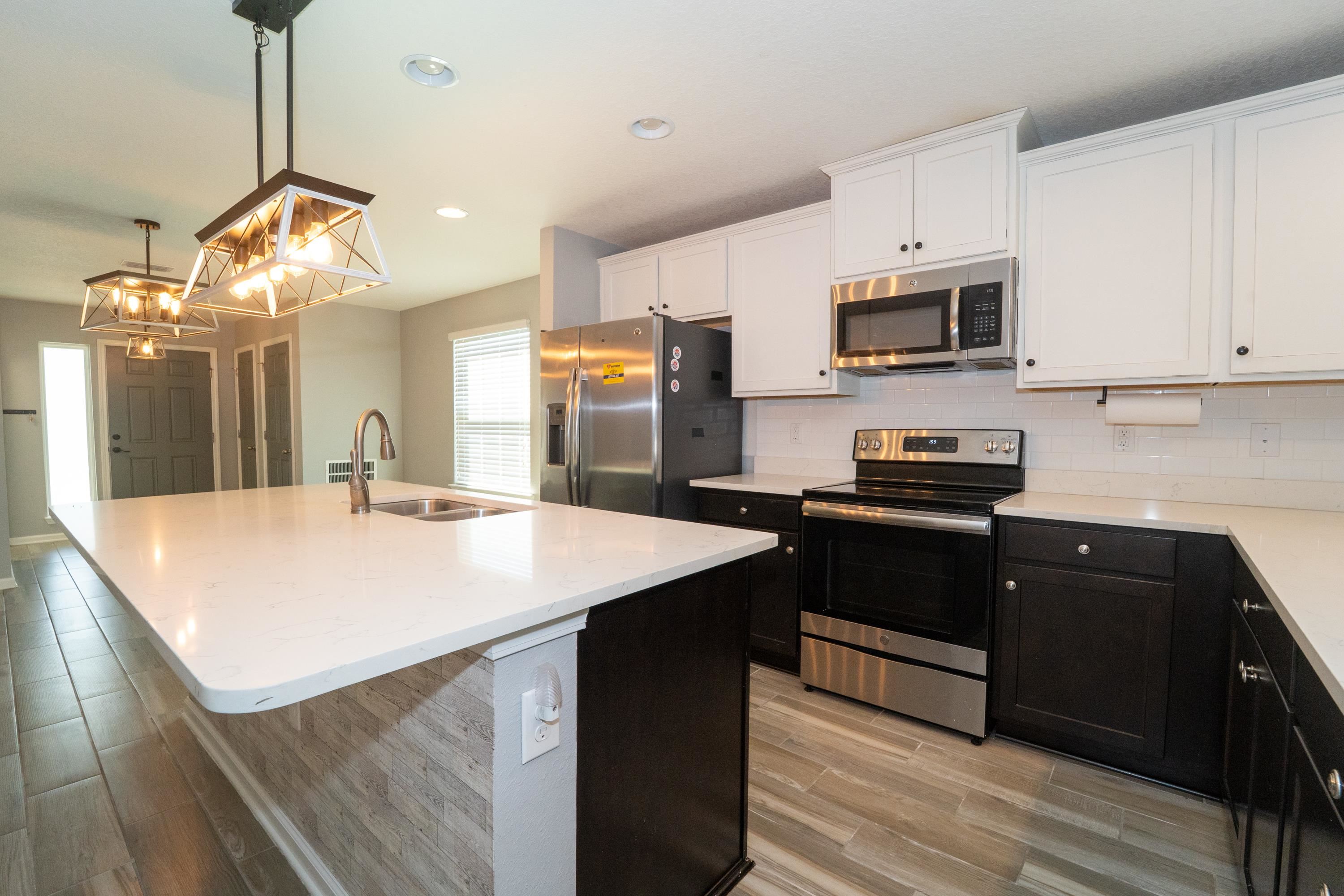 415 Santorini Court St. Augustine, FL 32086 - Photo 7 of 52 a kitchen with stainless steel appliances kitchen island granite countertop a refrigerator a sink dishwasher a stove and white cabinets with wooden floor