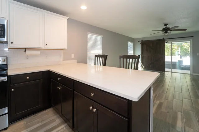 a kitchen with a sink dishwasher and white cabinets with wooden floor