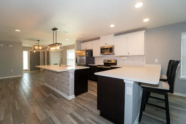 a large kitchen with kitchen island granite countertop a sink a stove a dining table and chairs