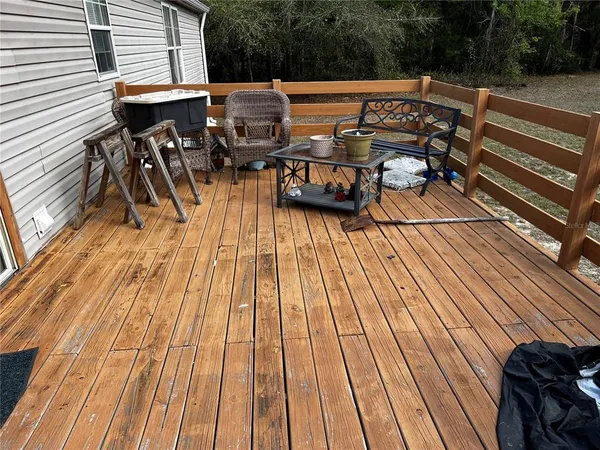 a view of deck with table and chairs a barbeque with wooden floor and fence