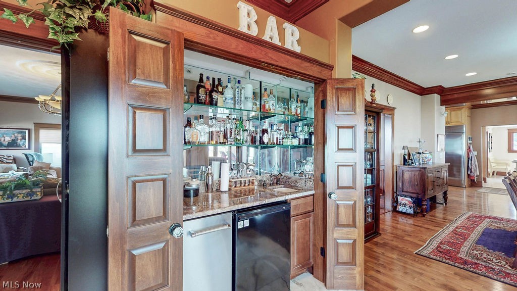 1431 Cedar Point Road Sandusky, OH 44870 - Photo 19 of 50 Indoor wet bar featuring black dishwasher, ornamental molding, light wood-style flooring, stainless steel built in refrigerator, and recessed lighting