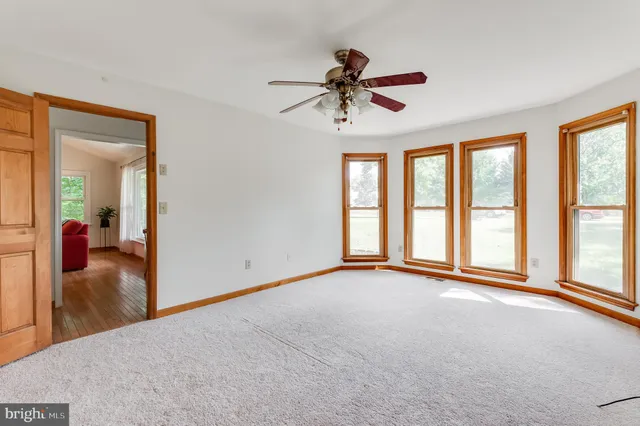 a view of an empty room with window and a kitchen