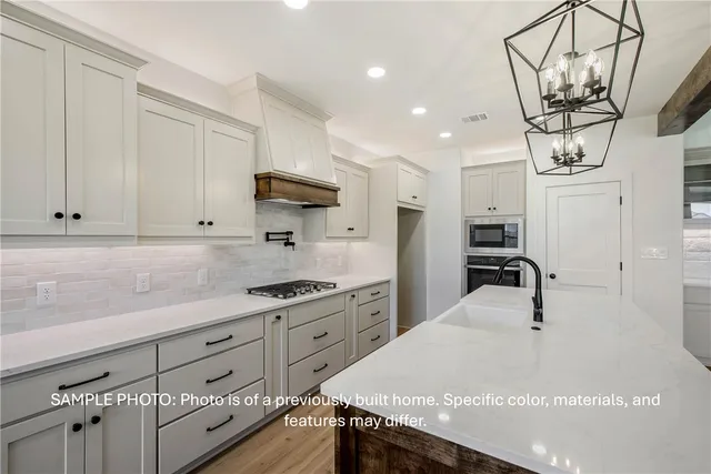a kitchen with stainless steel appliances granite countertop a sink a stove and cabinets
