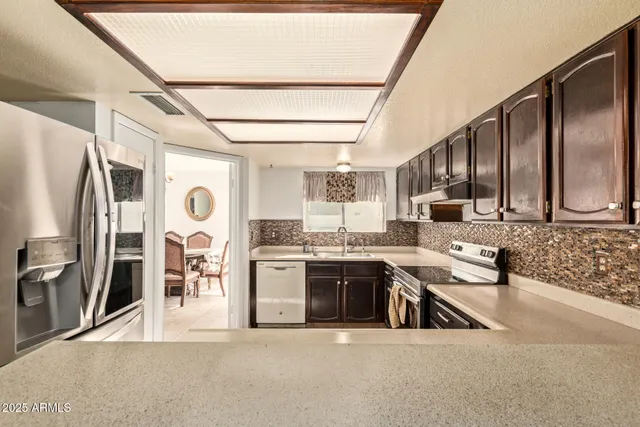 a kitchen with stainless steel appliances granite countertop a sink and a refrigerator