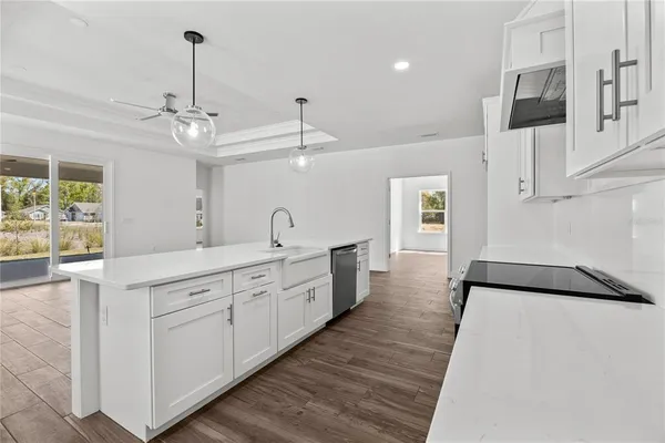 a large white kitchen with a lot of cabinets and wooden floor