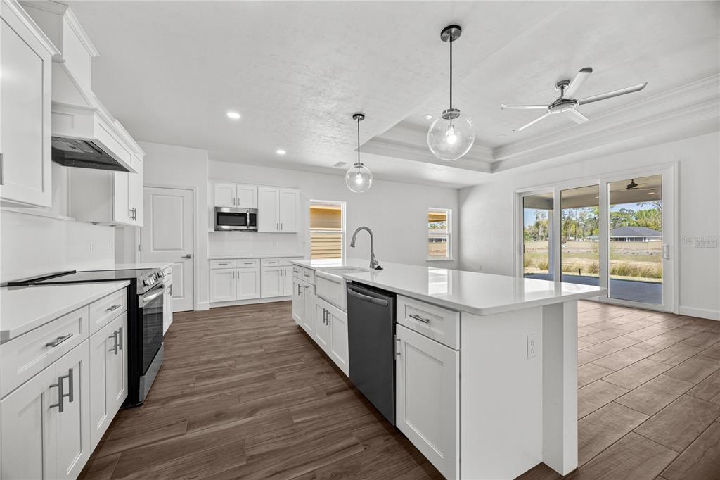 1132 Southwest 67th Drive Gainesville, FL 32607 - Photo 15 of 30 a large kitchen with stainless steel appliances granite countertop a sink and dishwasher a stove top oven with wooden floor