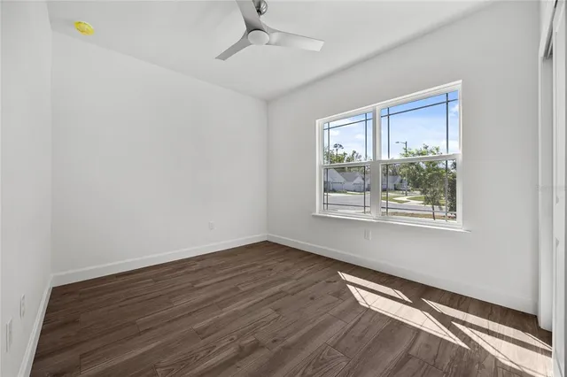 a view of an empty room with wooden floor and a window
