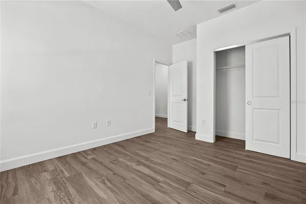 a view of an empty room with wooden floor and closet